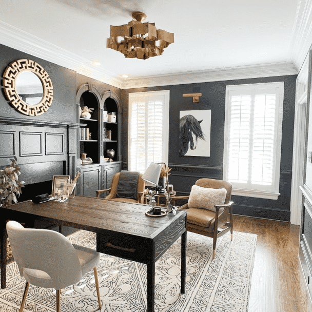 A large, elegant home office with a desk and 3 chairs and walls painted in iron ore sw 7069 by @alison_talleri_interiors.