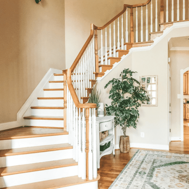 An elegant staircase in a foyer of a home painted in softer tan sw 6141 by @queenofthebeehive.