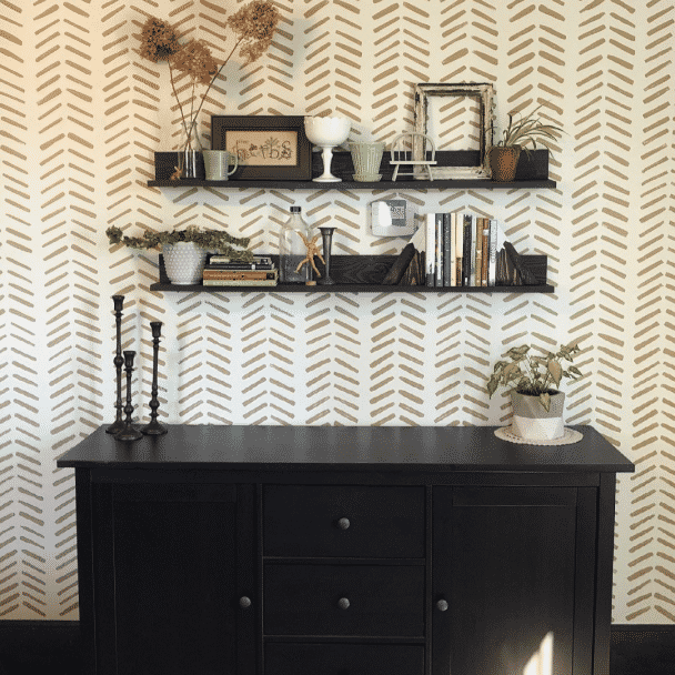 A patterned wall with 2 shelves and a dark wooden dresser in front. The walls are painted in origami white sw 7636 by @ylheidi.