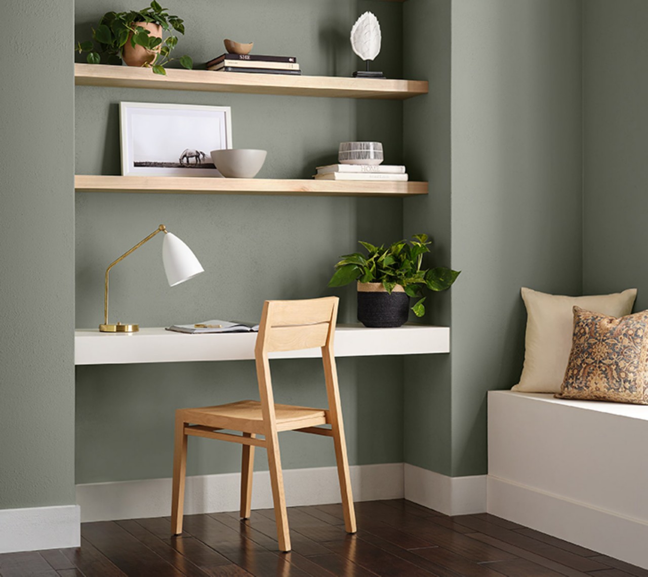 A minimalist office with floating wood shelves and Sherwin-Williams 2022 color of the year, Evergreen Fog painted walls.