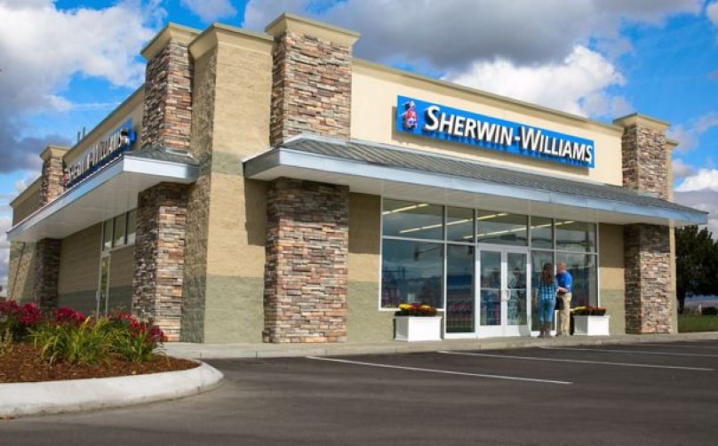 The exterior of a Sherwin-Williams store with an employee and customer talking near the front doors.