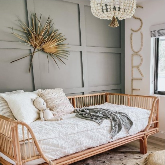 A rattan day bed in a toddler's room with the Sherwin-Williams 2022 color of the year, Evergreen Fog painted on the accent wall.