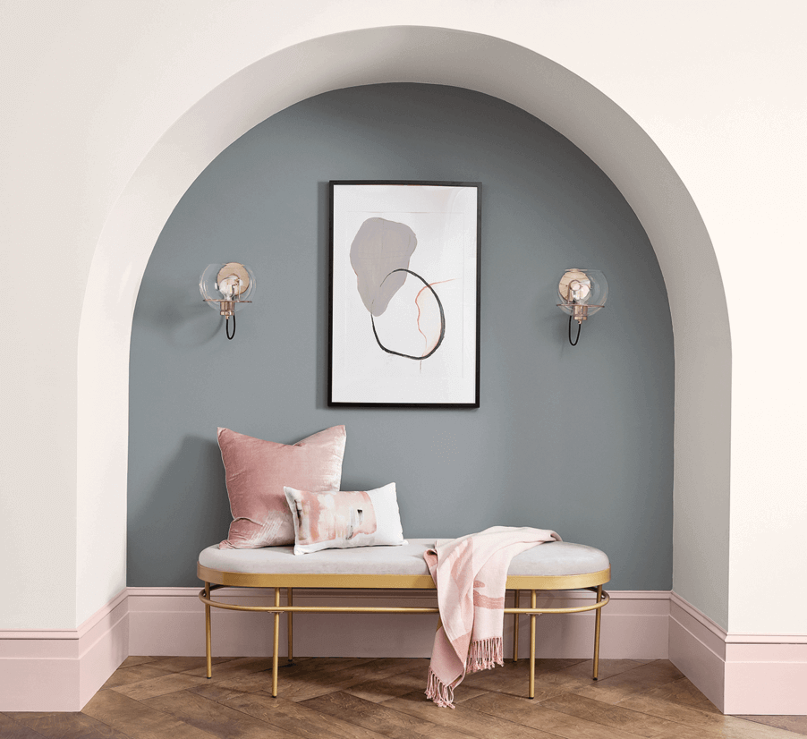 A hallway with a recessed area with an arch showing different levels of sheen on baseboards, walls, and the accent wall.