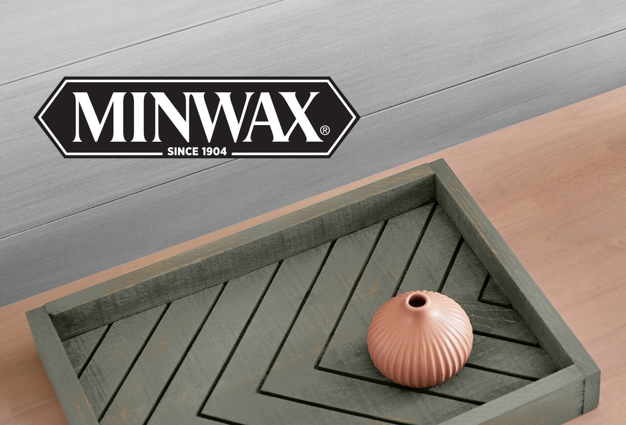 Minwax. Three colored wood stains on different wooden surfaces stacked on top of each other with a small brown vase on top. 