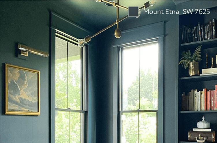An interior office featuring walls, window frames, and a bookshelf painted in Sherwin-Williams Mount Etna SW 7625, complemented with a gold decorative light fixture.