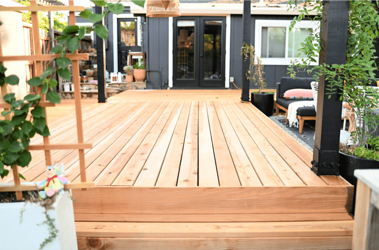 A new lightly stained walk out deck with patio furniture and plants.
