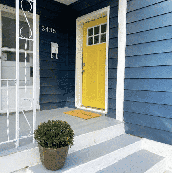 A blue shaded house with a yellow and white door with white front steps., by @thisflippinfamily