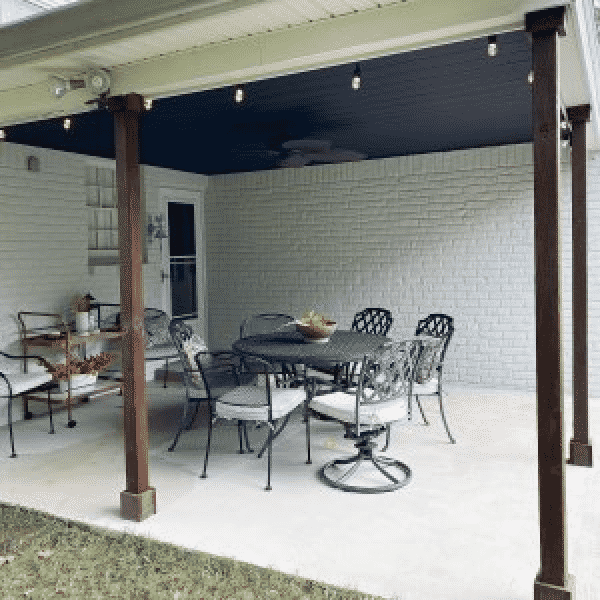 An outdoor covered patio with a white brick wall background, by sarah williams home.
