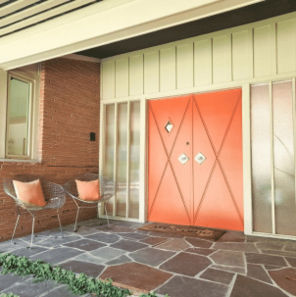 Orange double front doors with a stone walkway, by house down south.