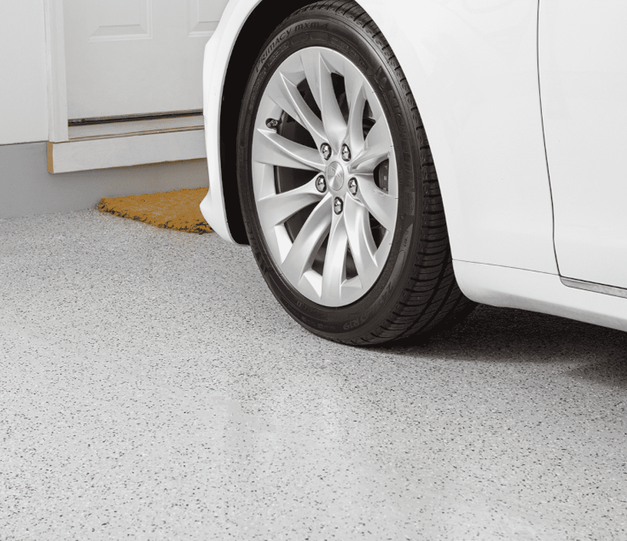 A white car in a garage with concrete flooring.