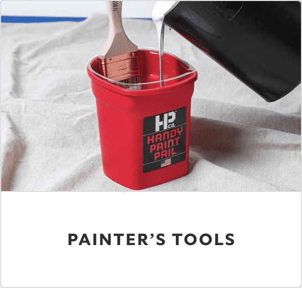 A red Handy Paint Pail on a drop cloth with a paint brush inside the bucket.