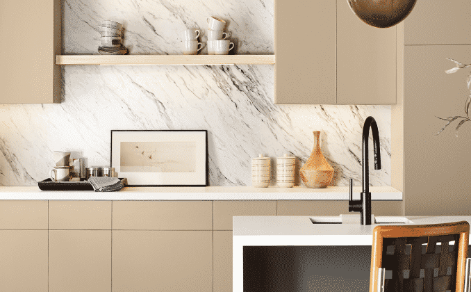 Marble backsplash with beige cabinets and neutral kitchenware.