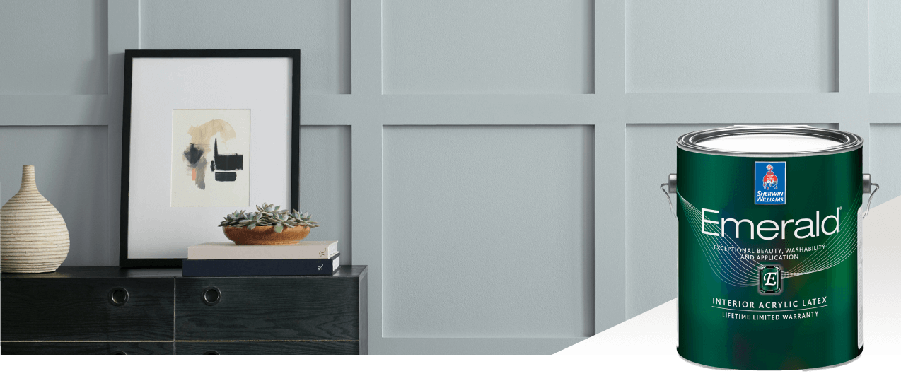A dark colored sideboard with a picture and vase against a bluish gray wall. Emerald interior acrylic latex.