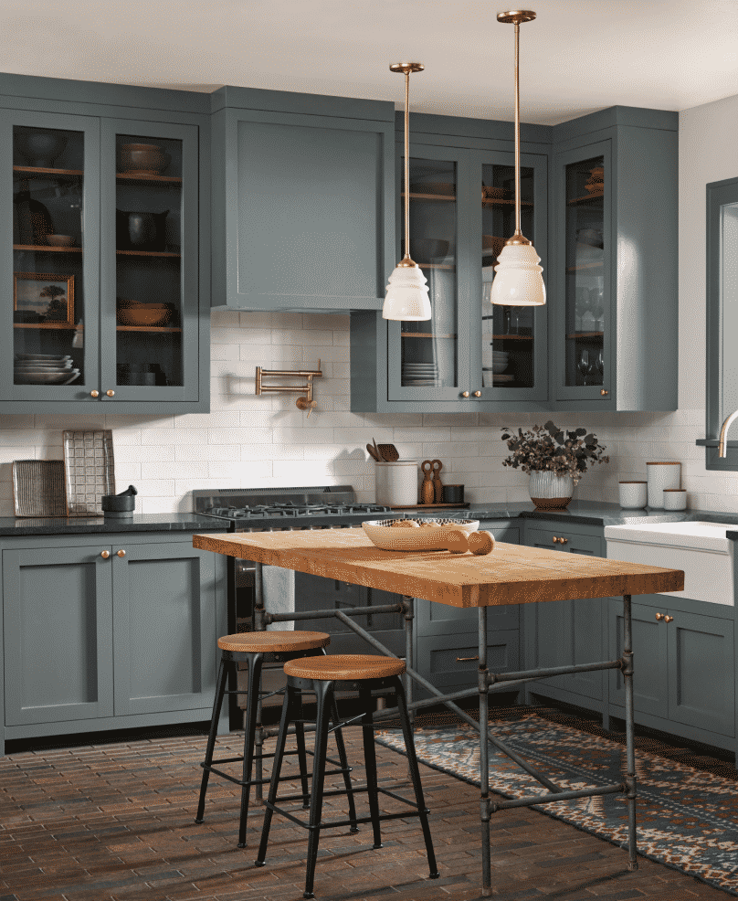Blue-grey cabinets in a kitchen with a wooden table and stools.