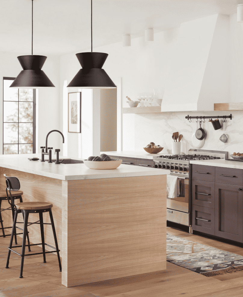 A white kitchen with large pendant lighting over the island that has a natural wood bottom and white countertop.