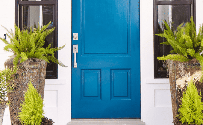 A front door painted Bosporus blue SW 6503 with large sidelights and potted ferns on each side.