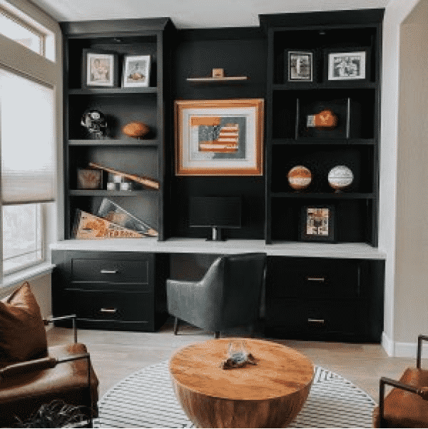 An office with floor to ceiling black built in desk and shelving. Two leather and metal chairs sit in the foreground around a solid wood table. Credit: Instagram @homecrushdesignsllc