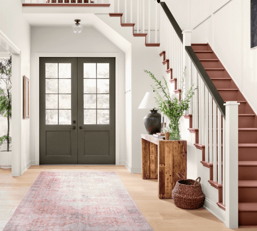 Entryway with white walls, double doors, patterned hallway rug, side table and steps.