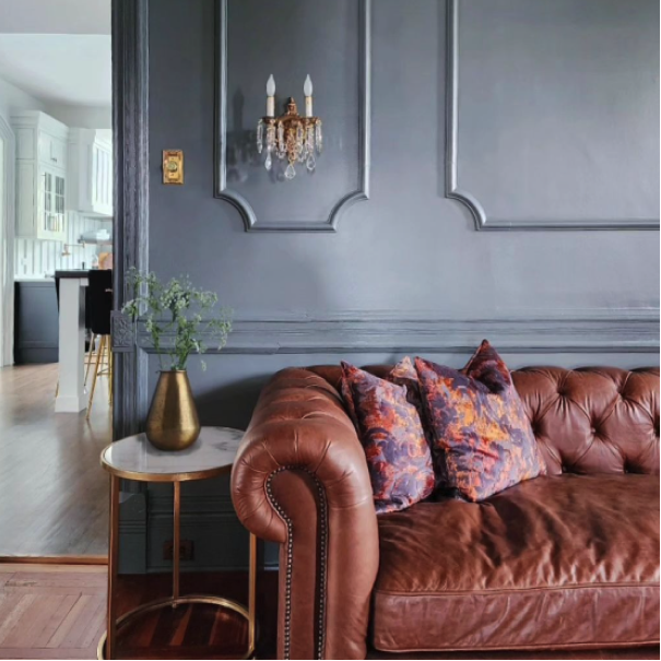 Living room painted in Roycroft Pewter with a dark leather couch, side table with plant, by @coreinteriordesign.