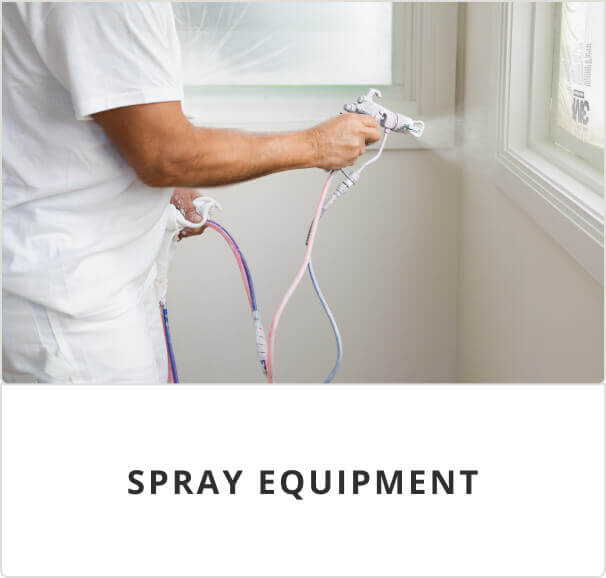 Spray equipment. A person in white painter clothes using a spray gun to spray white paint on a wall and window trim.