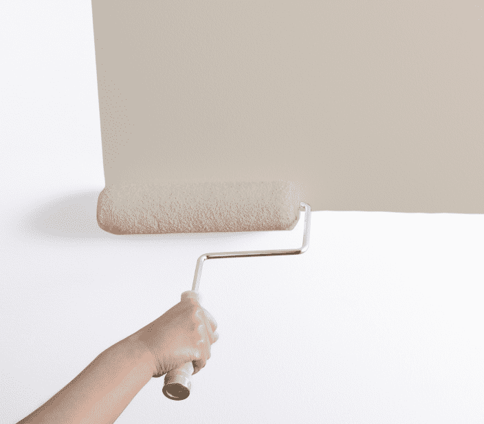 A person using a roller to paint a wall tan.
