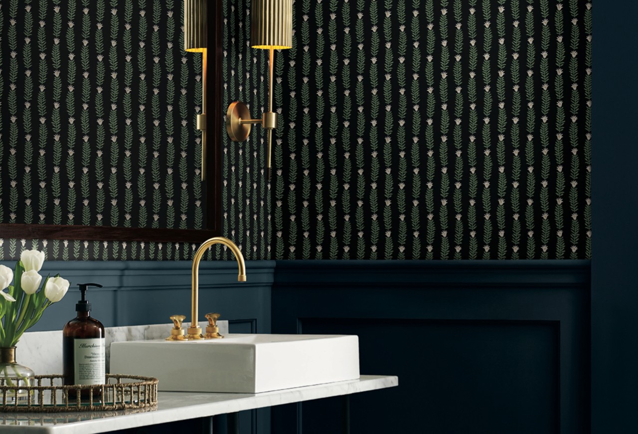 A bathroom with gold fixtures, dark painted wood and a dark striped pattern wallpaper.