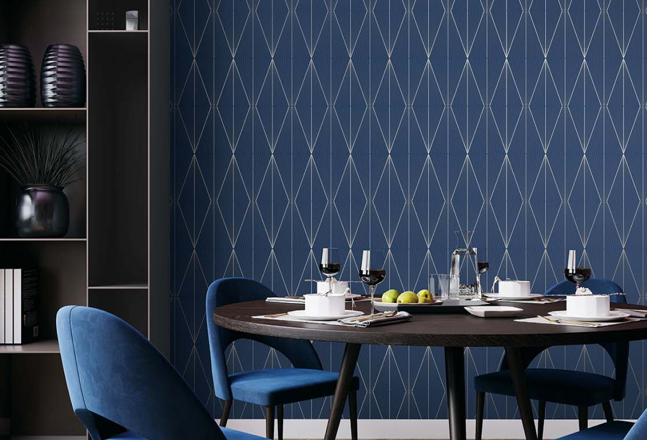 Blue geometrical wallpaper in dining room with a round wooden table and blue upholstered chairs. 