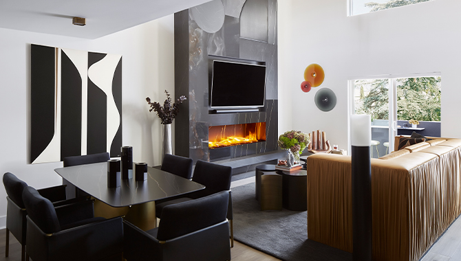 Modern living room and dining area with high ceilings, white walls, abstract artwork and modern fireplace and TV as focal point.