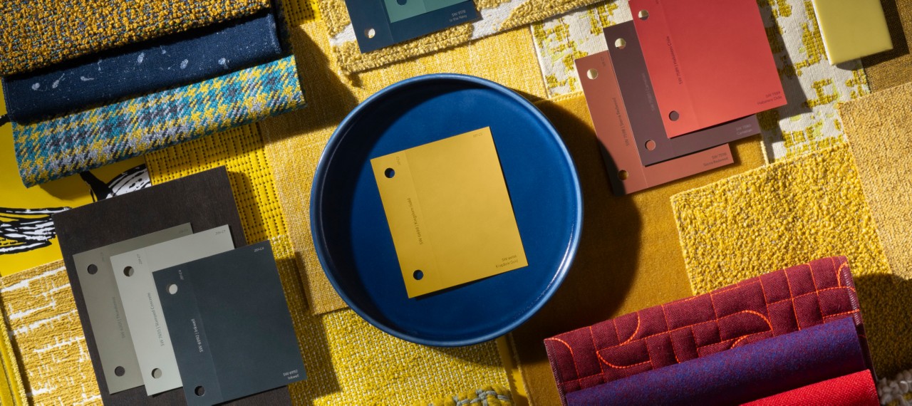 Flat lay of paint chips from The Loneliest Color™ by Sherwin-Williams x Dapper Dan Color Collection displayed with other coordinating fabrics and material swatches.