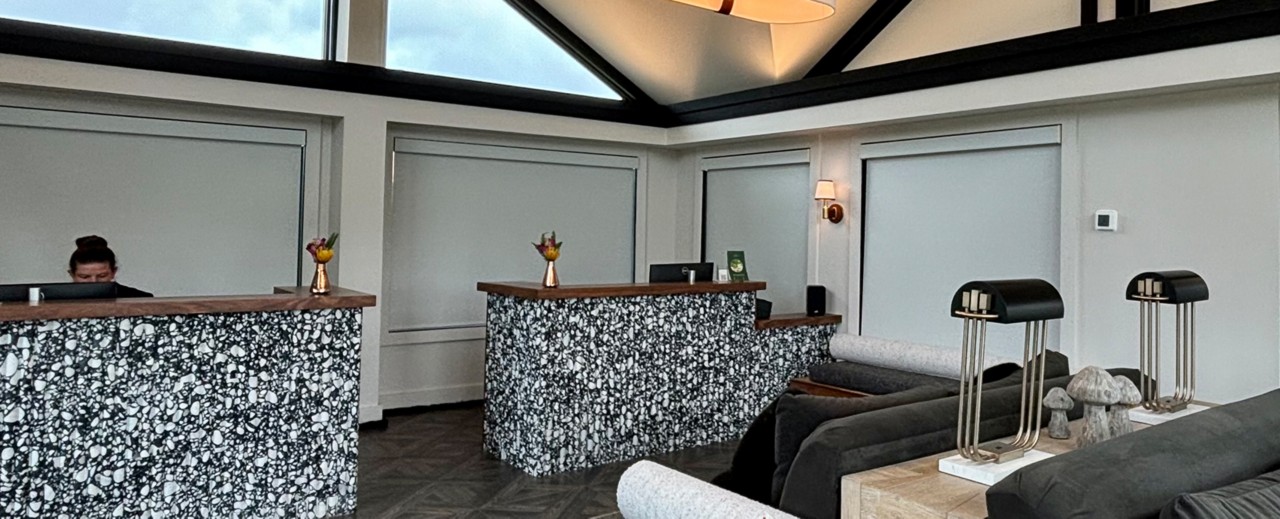 Modern reception area with variegated black and white counters, flower vases, skylights, and decorative elements.