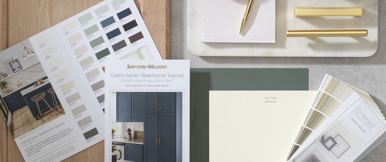 Bird’s-eye view of desktop featuring Sherwin-Williams color collection cards, fan deck, sample chips and gold hardware samples.
