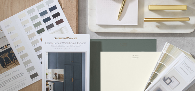 Bird’s-eye view of desktop featuring Sherwin-Williams color collection cards, fan deck, sample chips and gold hardware samples.