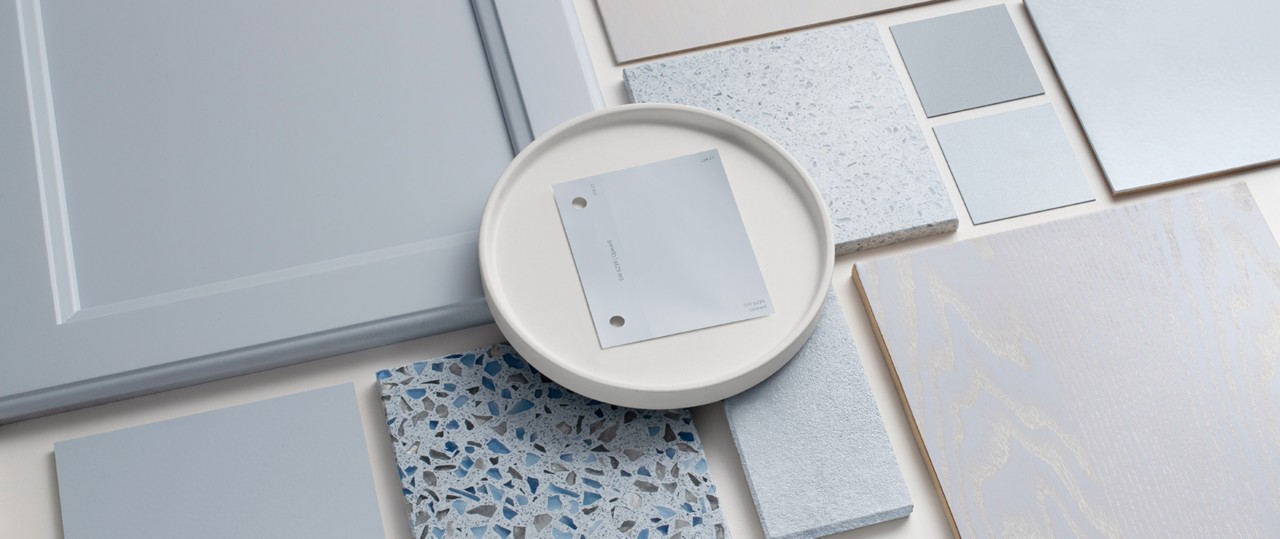 Flat lay featuring various substrates coated using the Sherwin-Williams gray-blue color: Upward, with a color sample chip on a small white plate in the center.