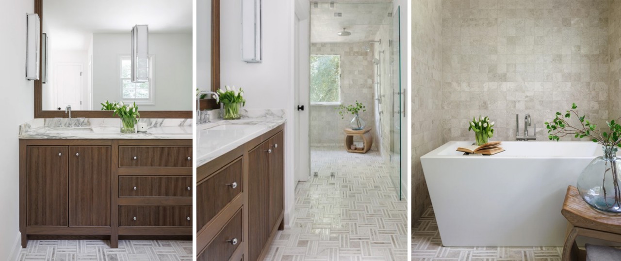 Bathroom with large vanity mirror over wood cabinetry, white walls and marble countertop and modern free-standing white bathtub in fully tiled niche.