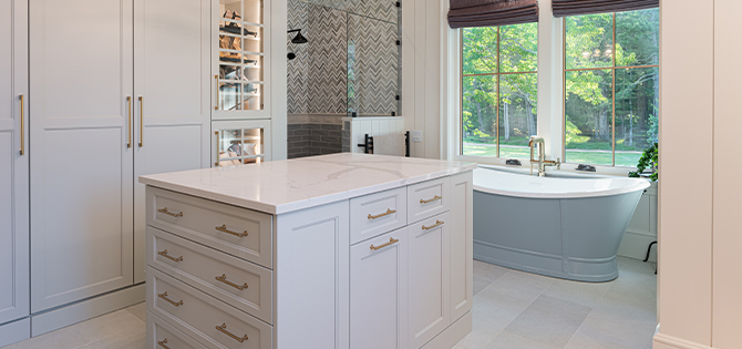 Spacious modern bathroom with freestanding tub in front of window, walk-in shower, lit cabinetry and center island.
