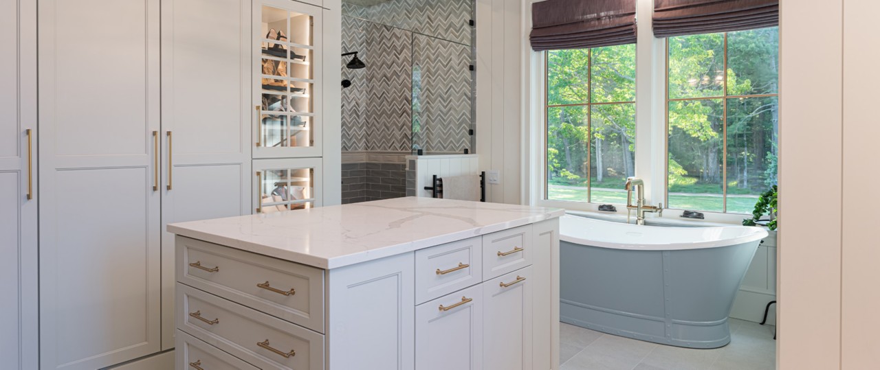 Spacious modern bathroom with freestanding tub in front of window, walk-in shower, lit cabinetry and center island.