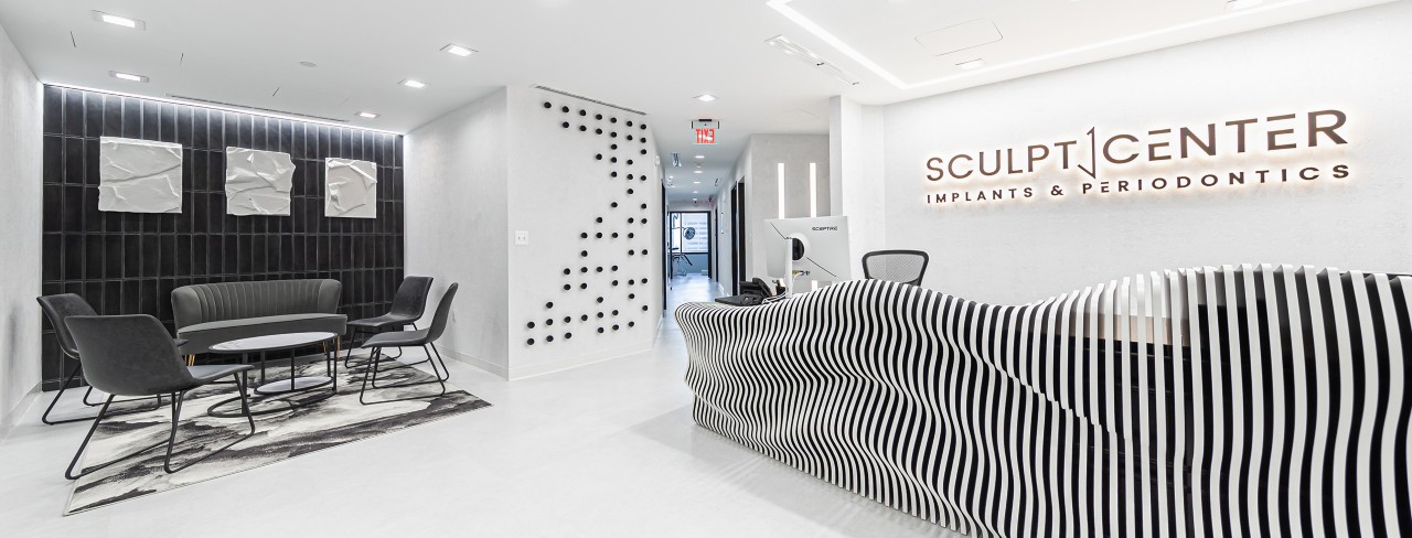 Lobby or reception area of Sculpt Center Implants and Periodontics with white and black color scheme and sculptural, undulating front desk.