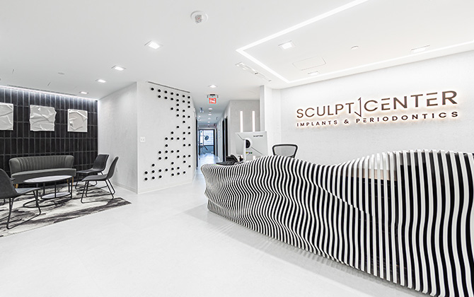 Lobby or reception area of Sculpt Center Implants and Periodontics with white and black color scheme and sculptural, undulating front desk.