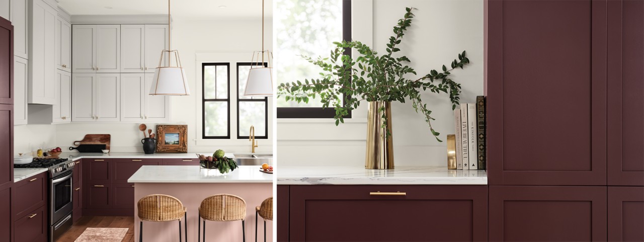 Brightly lit modern kitchen with marble countertops, center island painted pink, dark purplish red lower perimeter cabinets and white upper cabinets with bright metal hardware.