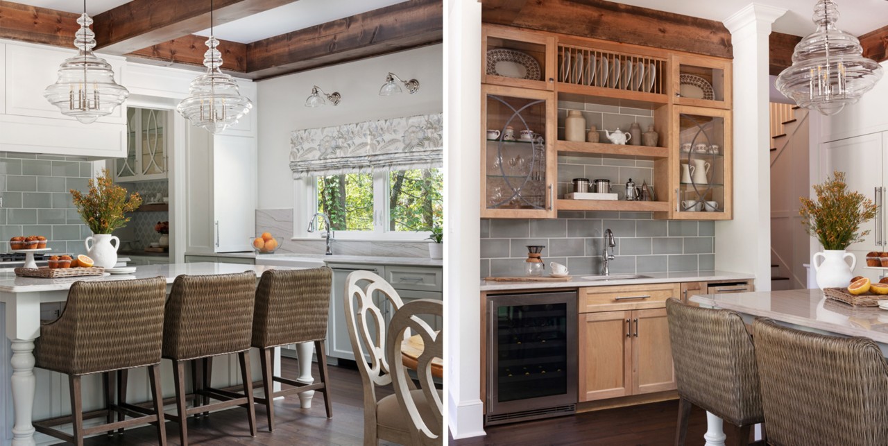Kitchen with white walls, glass-front wood cabinets, and natural wood ceiling beams, woven chairs at dine-in island, and two statement glass chandeliers.