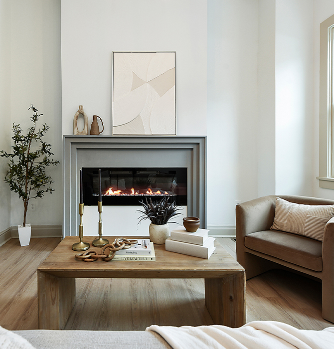 Modern living room with electric fireplace, neutral furniture, and large windows painted in Sherwin-Williams Pure White and Accessible Beige.