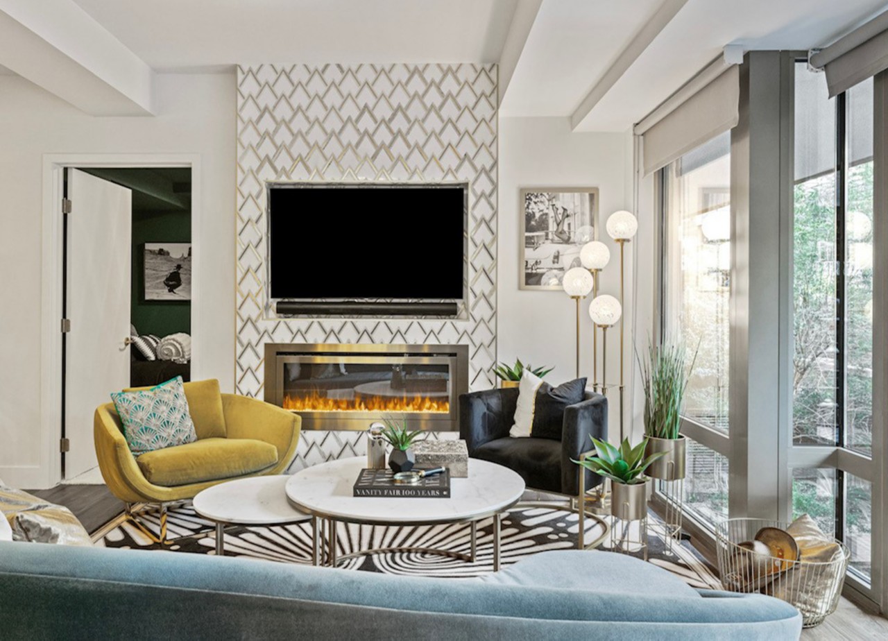Stylish living room with TV, electric fireplace, and modern furniture featuring a geometric patterned accent wall, surrounding walls painted Sherwin-Williams Pure White, and large windows.