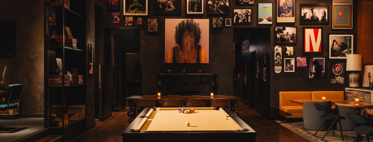 Stylish restaurant interior with a pool table, eclectic wall art, and cozy seating.