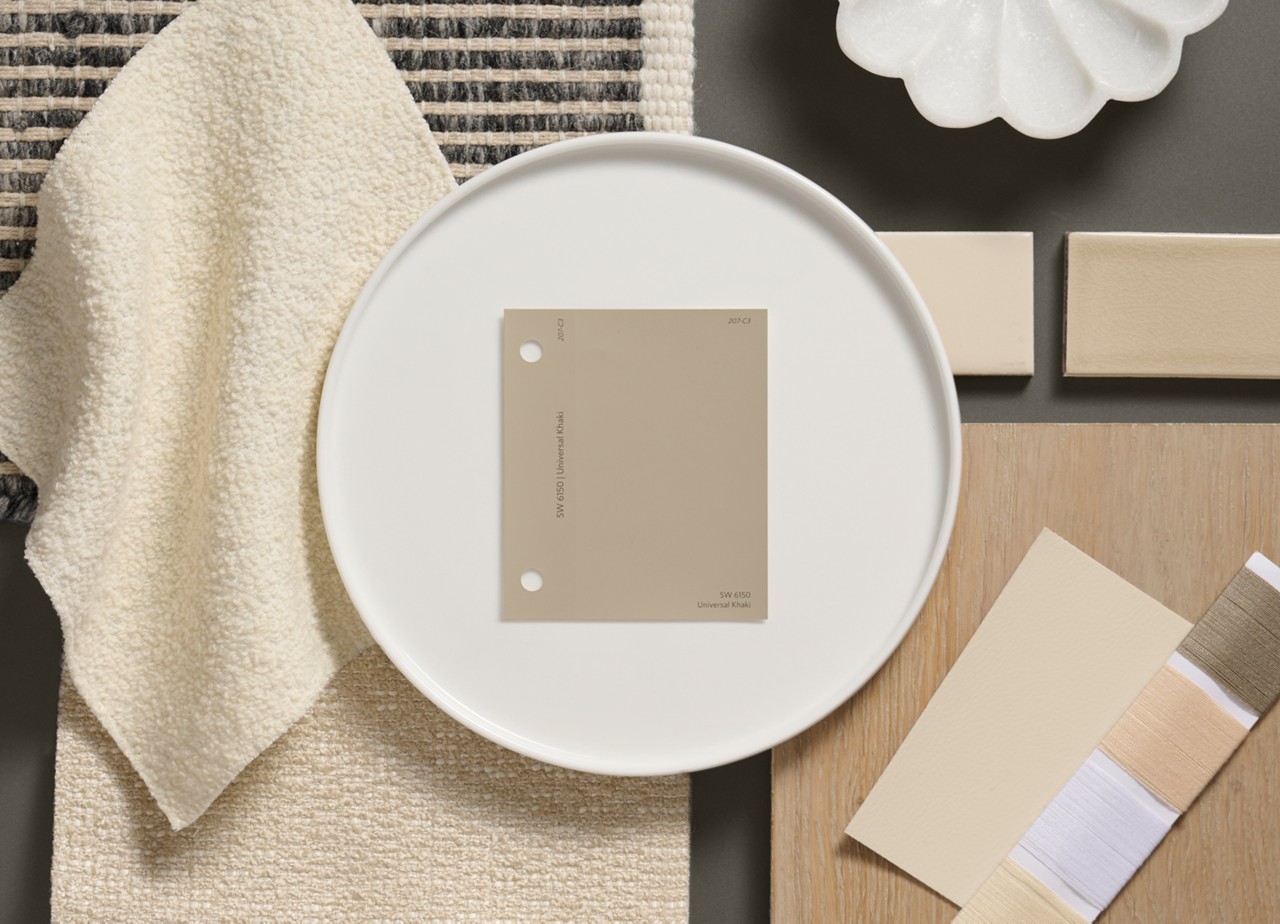 Flat lay of neutral-toned materials, featuring a Universal Khaki color swatch on a white plate, beige fabrics, tiles, and thread samples.