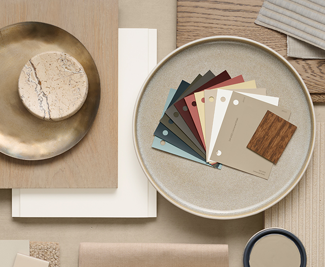 Flat lay of interior design materials including color swatches, a marble piece, brass dish, textile samples, and wood samples.