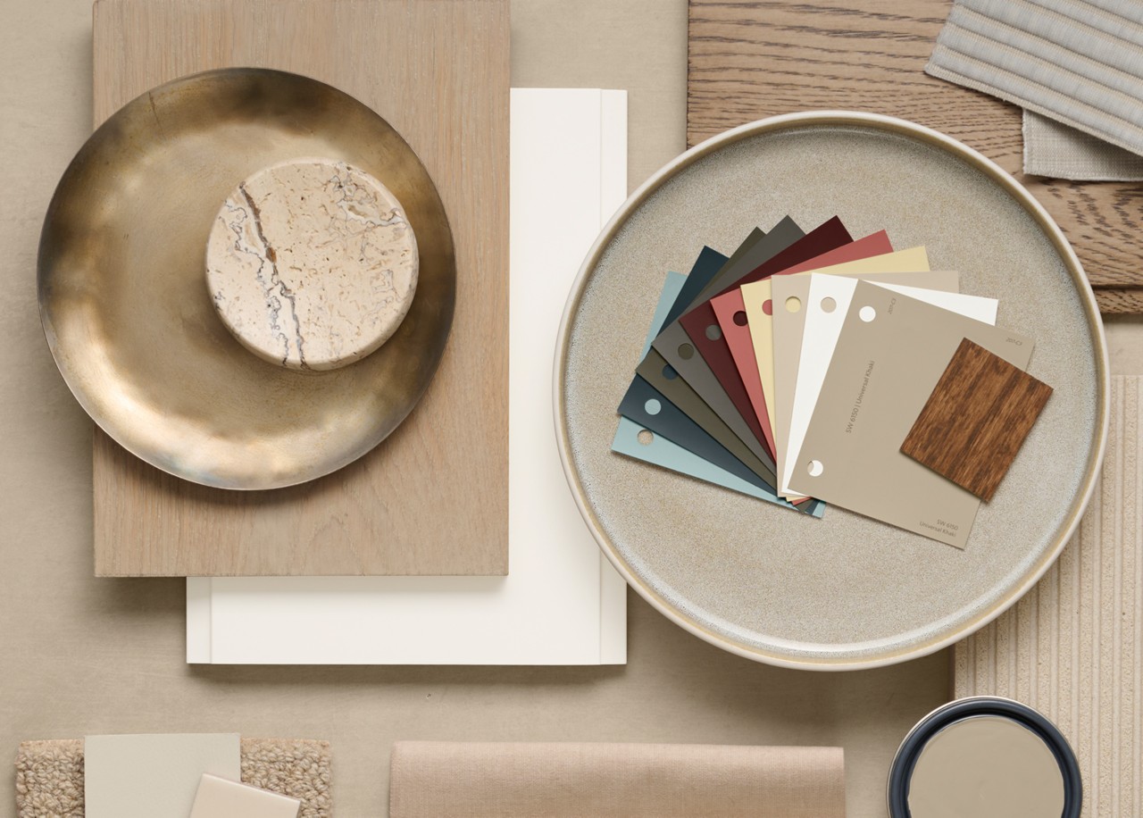 Flat lay of interior design materials including color swatches, a marble piece, brass dish, textile samples, and wood samples.