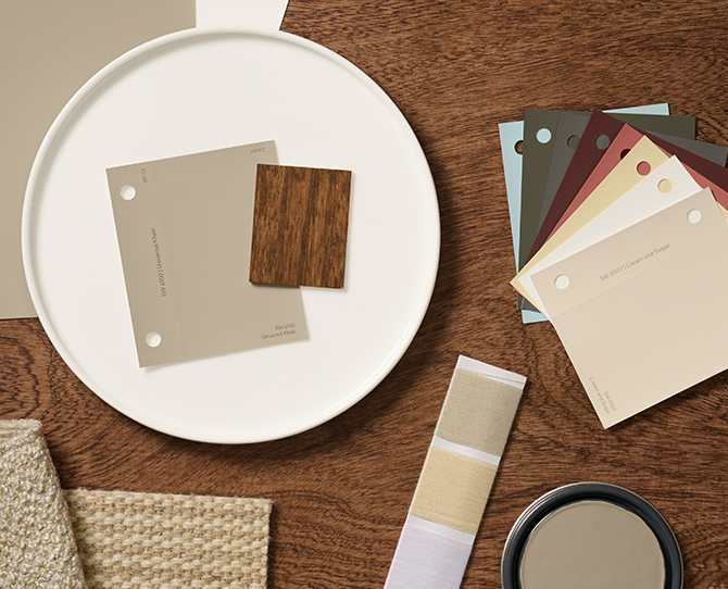 A flat lay of design materials including color swatches, fabric samples, and a wood sample of Minwax Special Walnut stain arranged on a wooden surface.