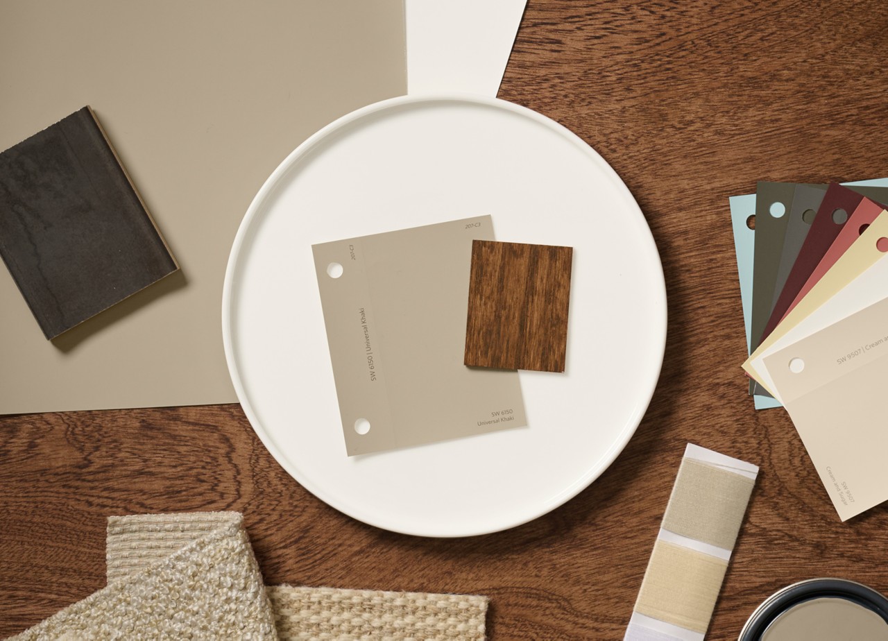A flat lay of design materials including color swatches, fabric samples, and a wood sample of Minwax Special Walnut stain arranged on a wooden surface.