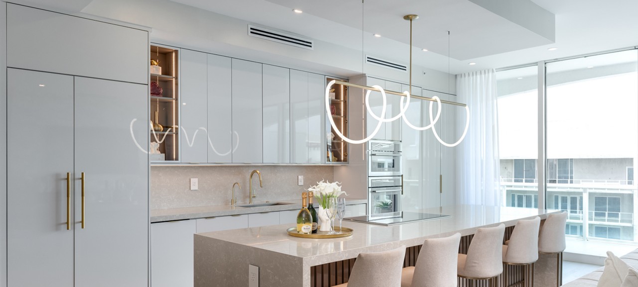 Modern kitchen with a light and airy color scheme, including white cabinets, stone countertops, and beige accents. 