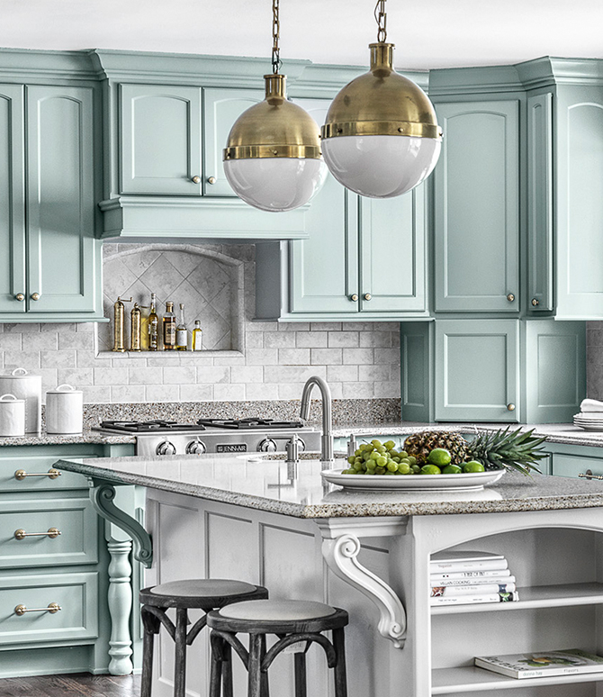 Modern kitchen with light blue-green cabinets and stainless steel appliances. 